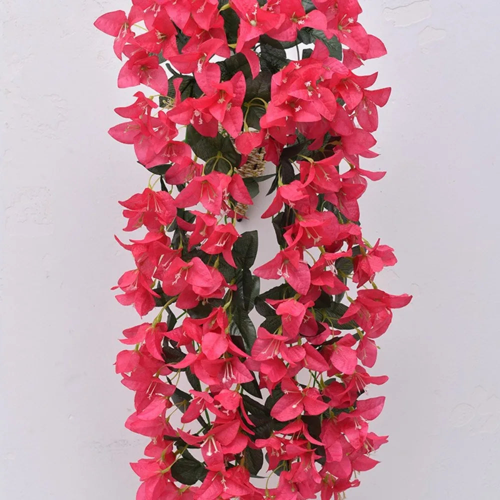 A long, vibrant pink faux bougainvillea vine with dark green leaves hanging vertically.