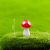 A small red and white resin mini mushroom figurine placed on green grass.