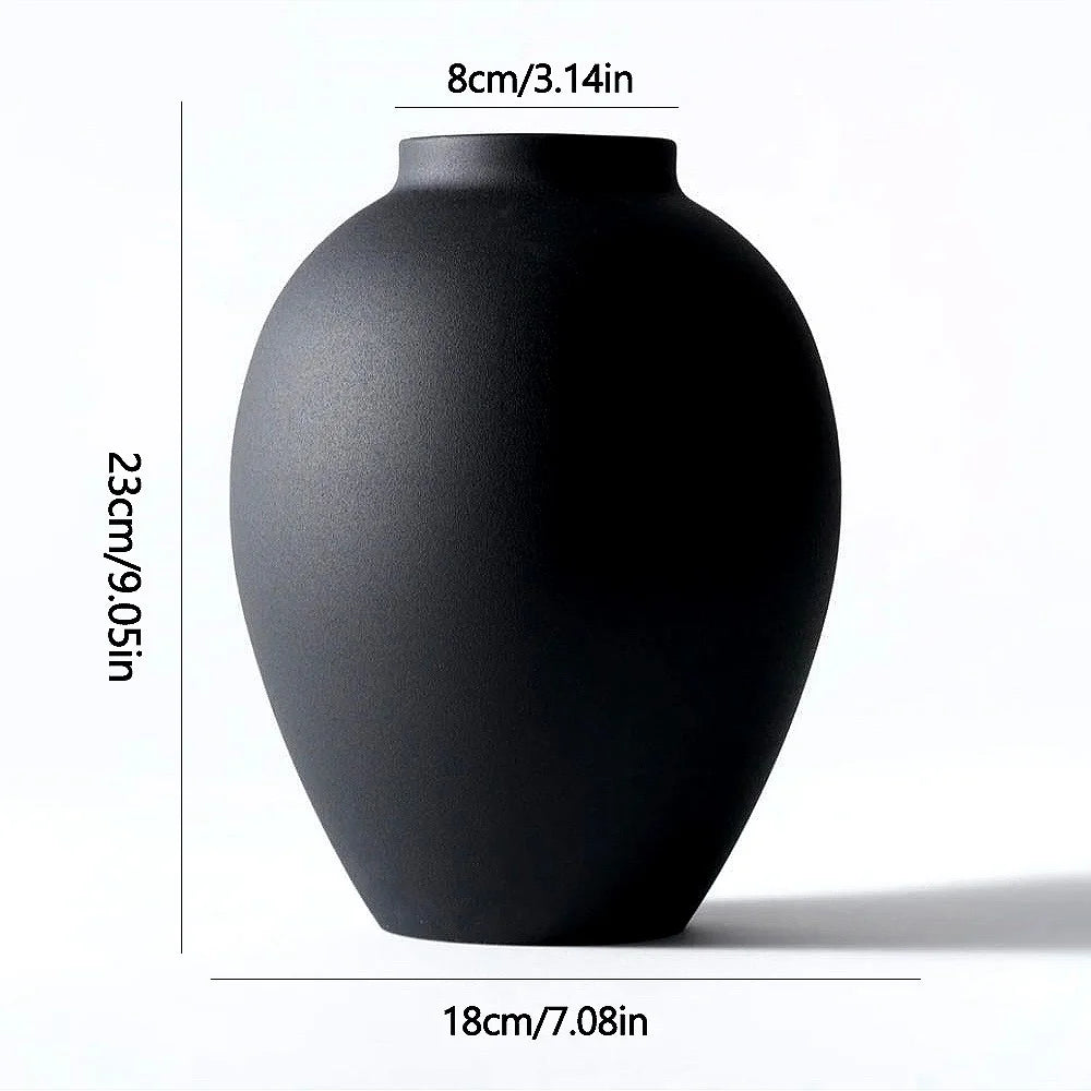 A matte black modern round metal decorative vase shown from the side.