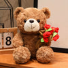 A brown teddy bear plush toy with a white face and a bouquet of red roses attached to its chest.