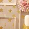Metallic gold and silver star paper garland bunting hanging against a light beige wall.