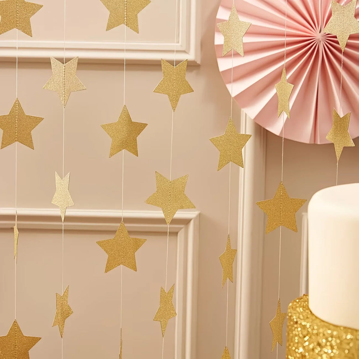 Metallic gold and silver star paper garland bunting hanging against a light beige wall.