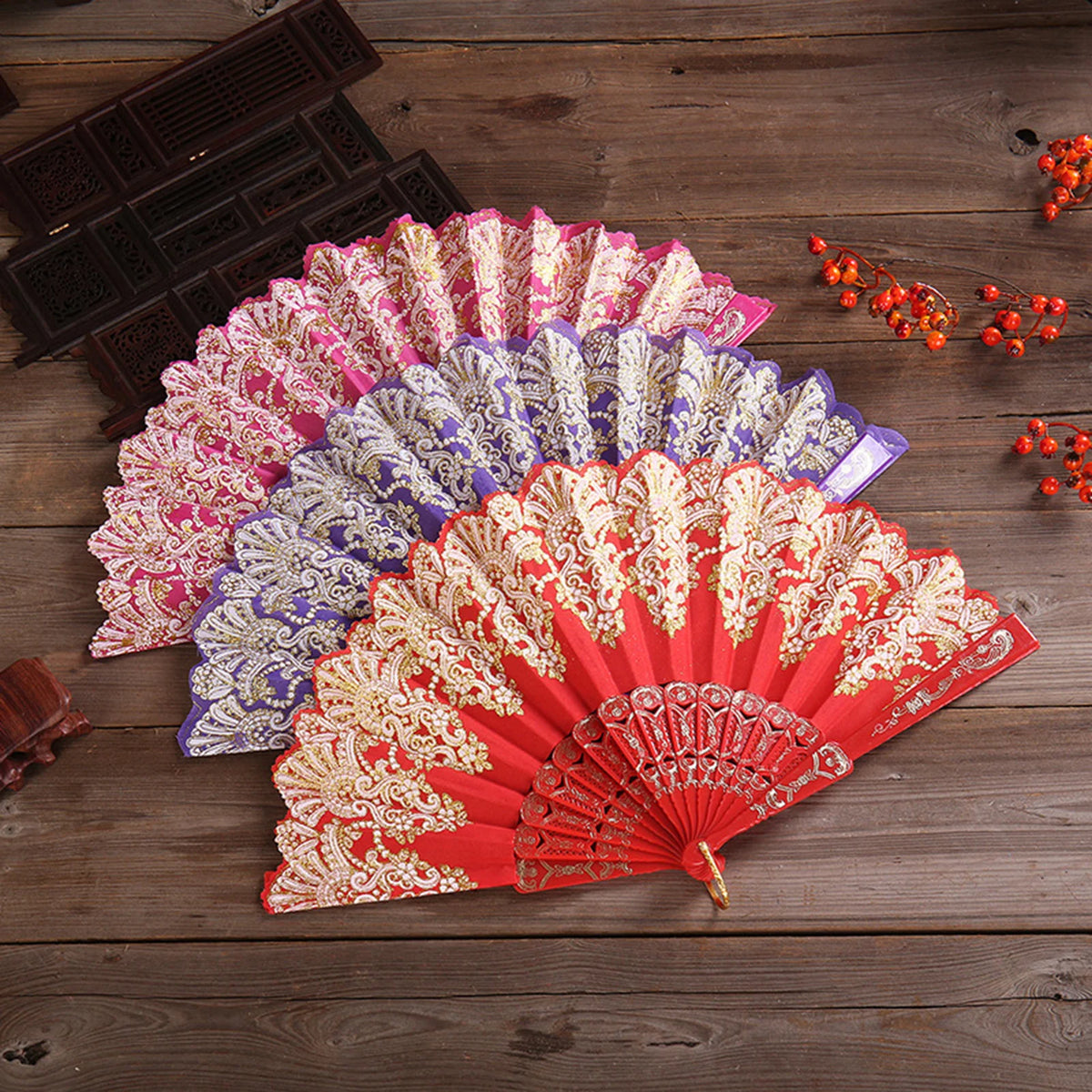 A display of multiple elegant folding fans in shades of pink, purple, and red with intricate traditional Chinese designs.