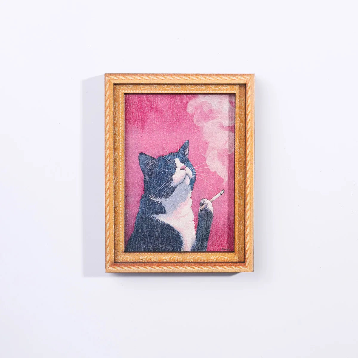 A painting of a black and white cat smoking a cigarette, framed in wood.