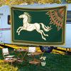 A green tapestry flag featuring a golden horse in a leaping pose, displayed on the side of a white RV.