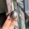 Silver vintage marine life brooch pin set shaped like a sea turtle being held by a hand
