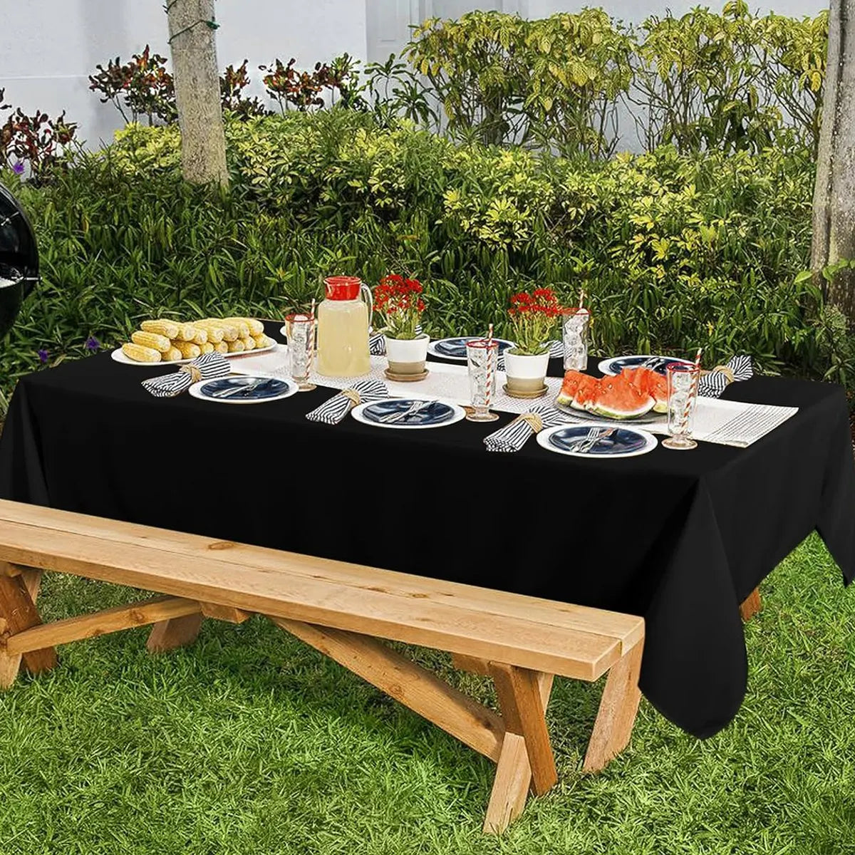 Elegant black disposable plastic tablecloth set for outdoor parties with food and drinks