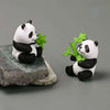 A set of mini resin panda bonsai figurines, one holding a green leaf.