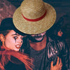 A close-up portrait of a person wearing a straw hat and dark clothing with dramatic makeup.