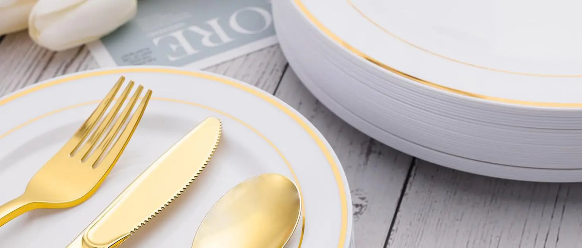 Service de table en plastique jetable avec couverts et bordure dorée sur une assiette blanche.