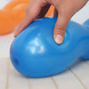 A hand is squeezing a bright blue spiral twist latex balloon on a white surface.