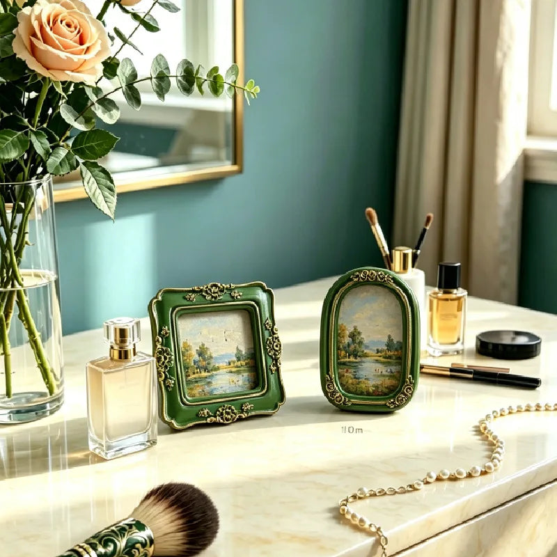 A vintage baroque resin picture frame in green holds a small glass bottle on a marble surface.