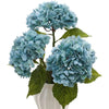 A cluster of light blue artificial hydrangea flowers on green leaves in a white pot.