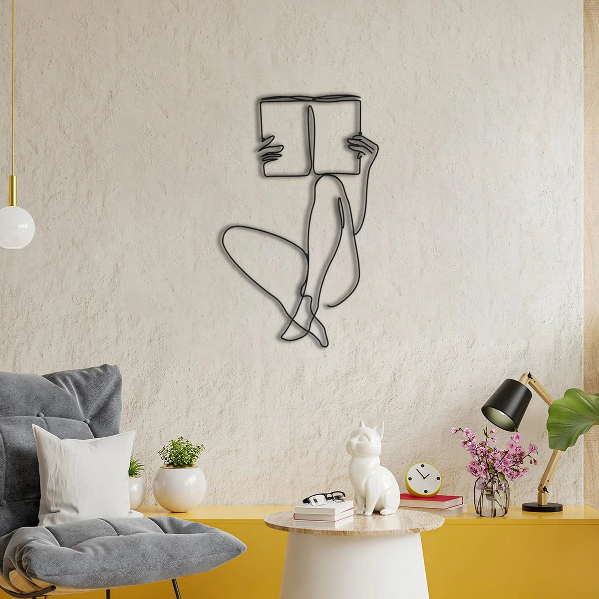 A minimalist line art wall decor featuring a figure reading a book on a textured white wall.
