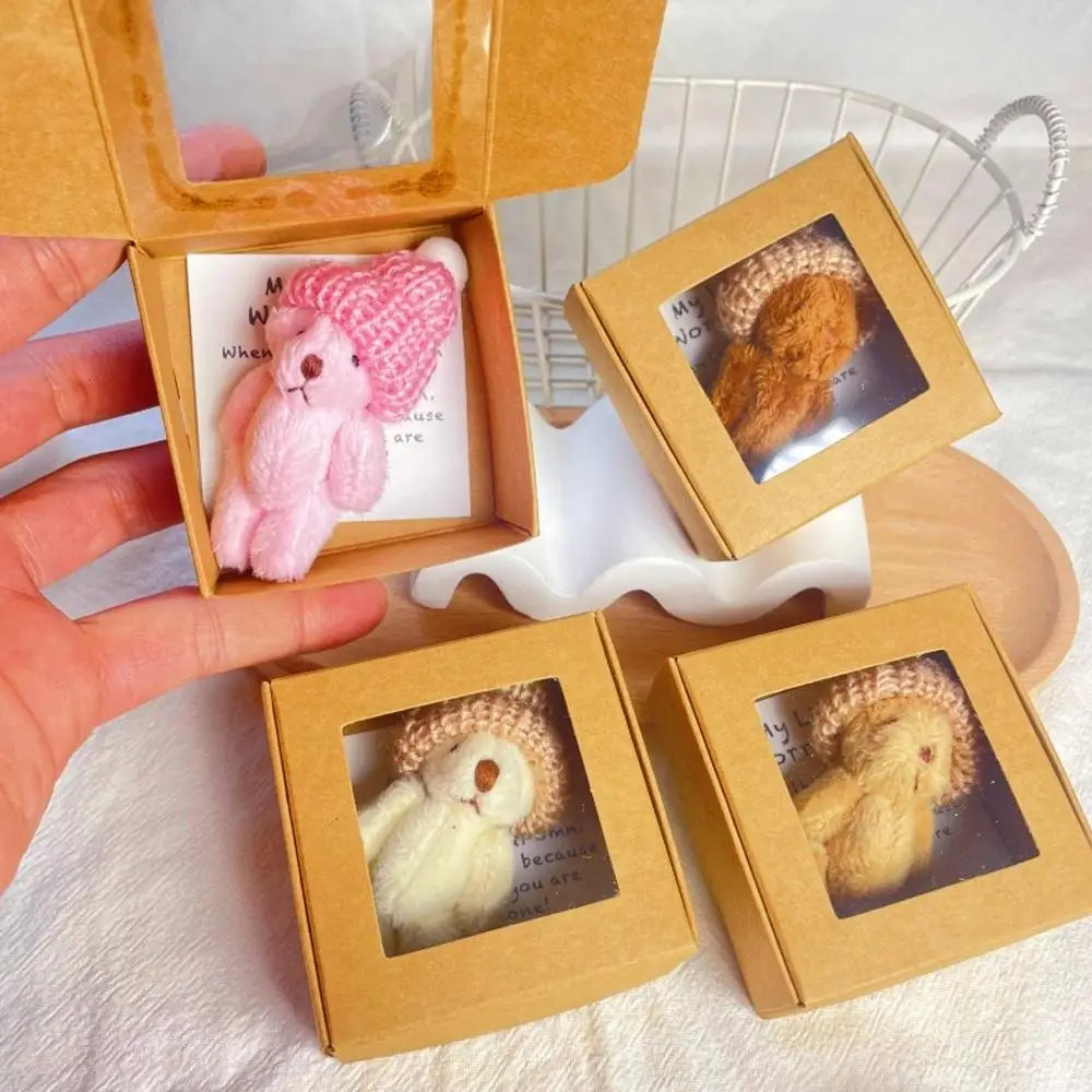 Un set de ositos de peluche mini en rosa y beige con tarjetas inspiradoras, presentados en cajas de madera.