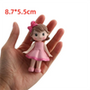 A small pink ballerina figurine with brown hair and a pink bow, shown held in a hand.