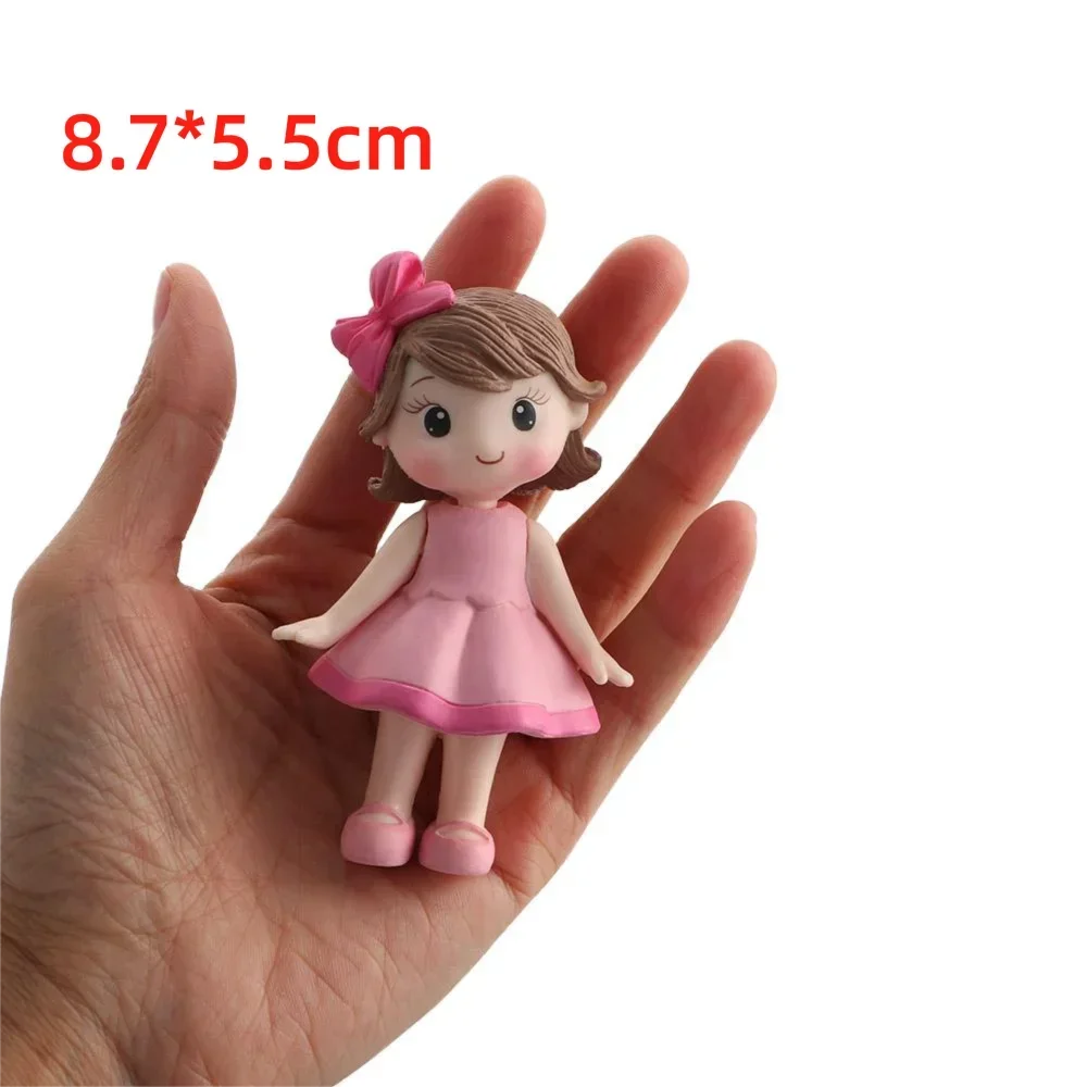 A small pink ballerina figurine with brown hair and a pink bow, shown held in a hand.