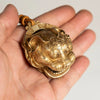 A brass tiger head bell with an ornate design is held in a person's hand.