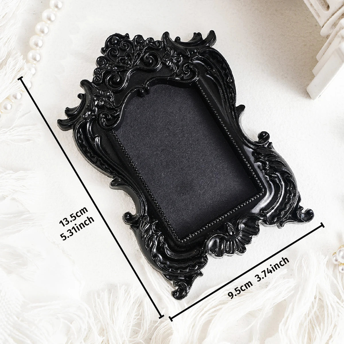 Black ornate resin wall decor pendant framed in a decorative shape on a white surface