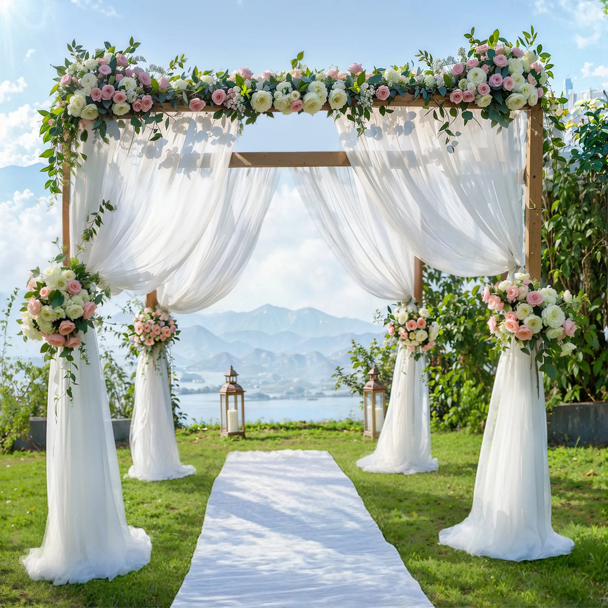 An elegant outdoor wedding backdrop featuring a wooden arch decorated with lush floral arrangements and sheer white tulle dra