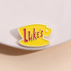 A yellow enamel pin featuring the word Luke's in red text on a white background.
