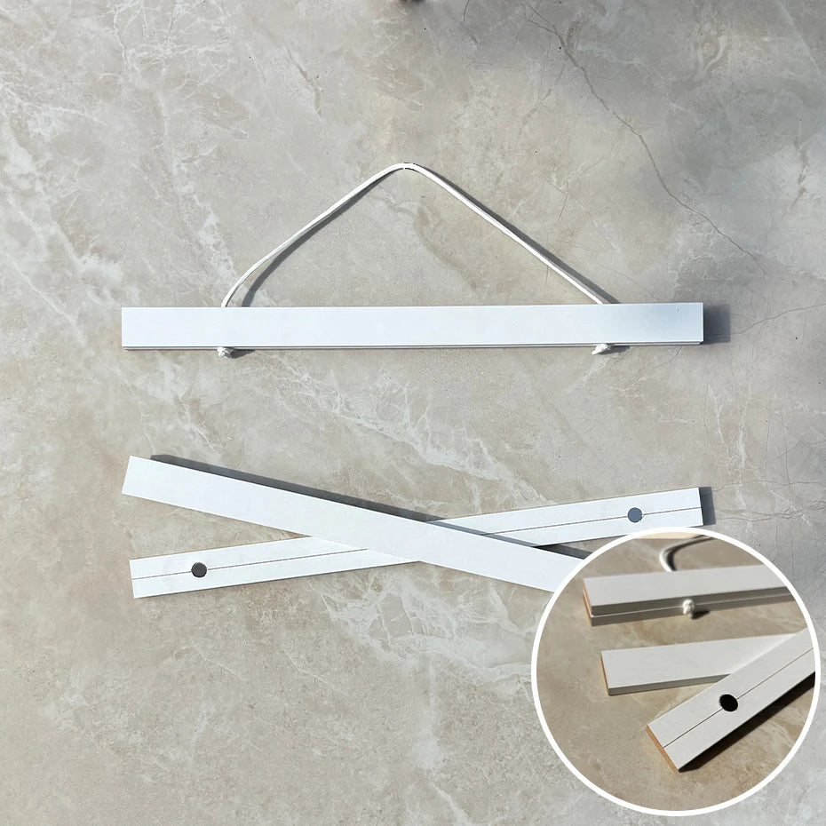 A natural teak wood magnetic poster frame displayed on a light gray concrete surface.