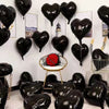 A collection of black heart-shaped foil balloons displayed against a white wall.