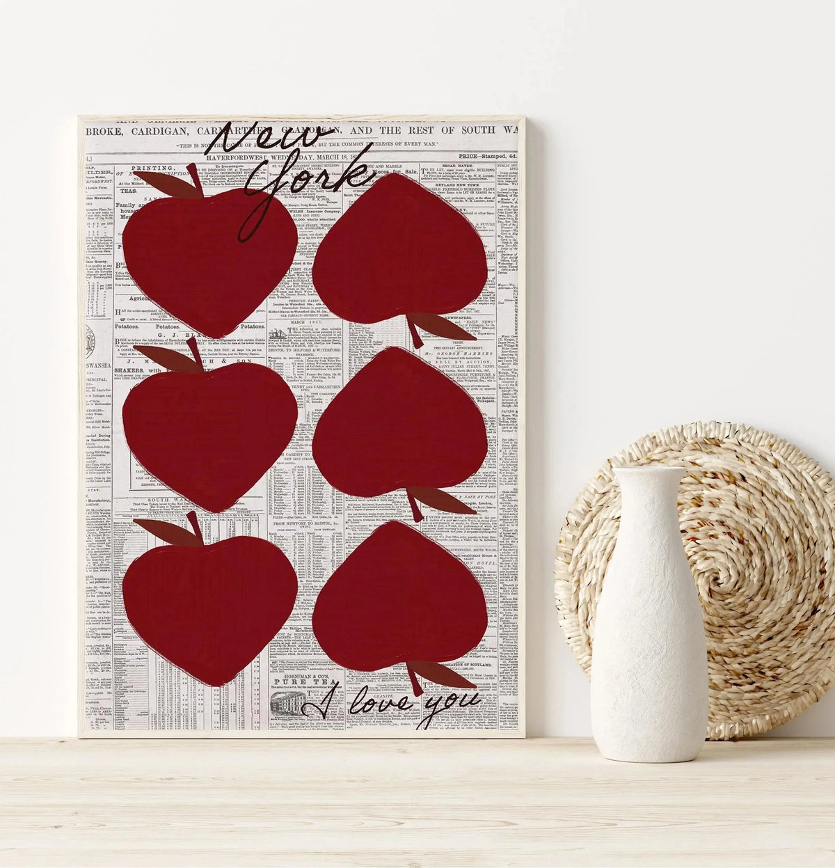A framed art print featuring red apple silhouettes on a vintage newspaper background.