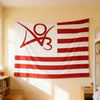 Une grande tapisserie en tissu avec un drapeau rayé rouge et blanc sur un mur jaune clair.