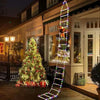 A glowing neon light shaped like a Santa Claus climbing ladder decoration is displayed in front of a house with a decorated C