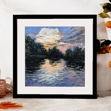 A framed oil painting depicting a sunset reflection on water with silhouetted trees and clouds.