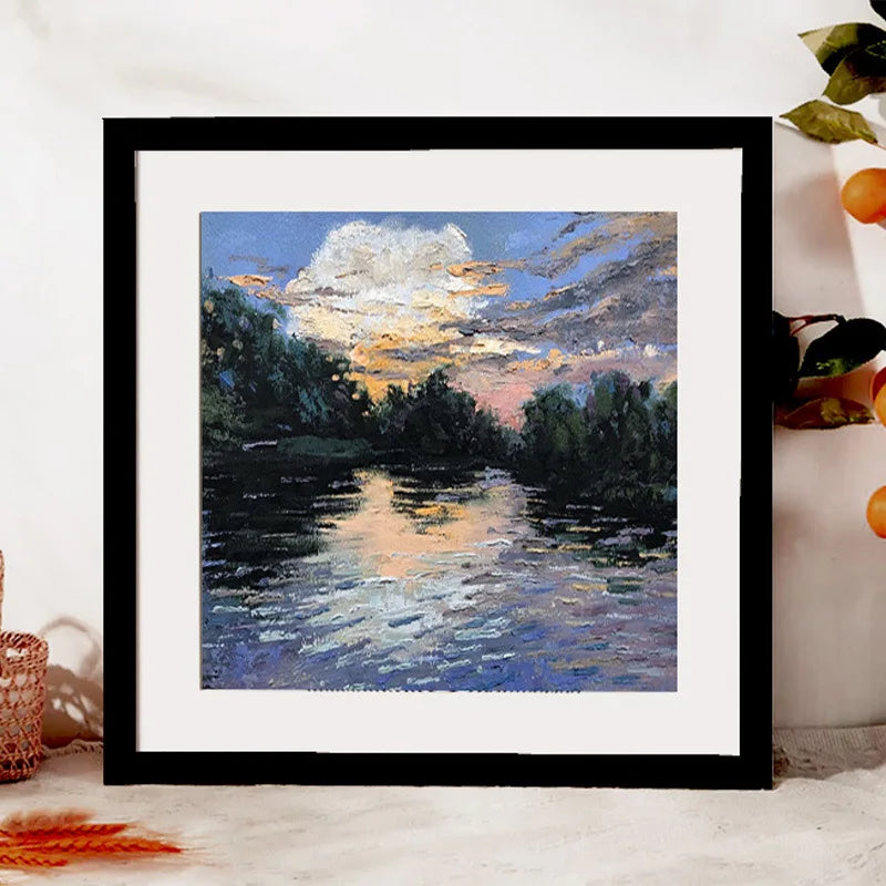 A framed oil painting depicting a sunset reflection on water with silhouetted trees and clouds.