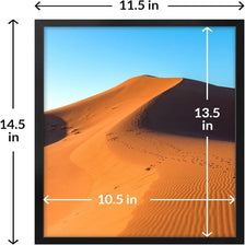 A black picture frame displaying a landscape of orange and brown sand dunes under a clear blue sky.
