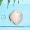 A light pink seashell with ridges and a small golden starfish rests on a bright blue wooden surface.