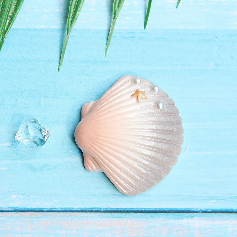 A light pink seashell with ridges and a small golden starfish rests on a bright blue wooden surface.