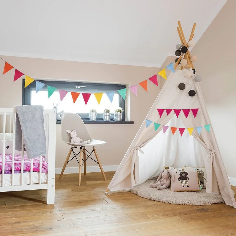 A child's nursery decorated with a teepee tent and colorful pennant banners.