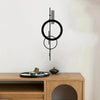 Schwarzes minimalistisches, geometrisches Wandskulptur mit konzentrischen Kreisen und vertikalen Linien an einer weißen Wand.