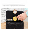 A hand is holding a black compact folding table bag with gold hooks, demonstrating its use as a portable purse hanger.