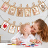 A woman is holding a baby while decorating a banner with monthly growth records for a baby's first birthday.