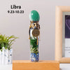 A glass bottle filled with natural healing stones and topped with a green crystal, representing the Libra zodiac sign.