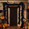 A dark green tinsel ribbon garland frames a doorway decorated for Halloween with pumpkins and autumn leaves.