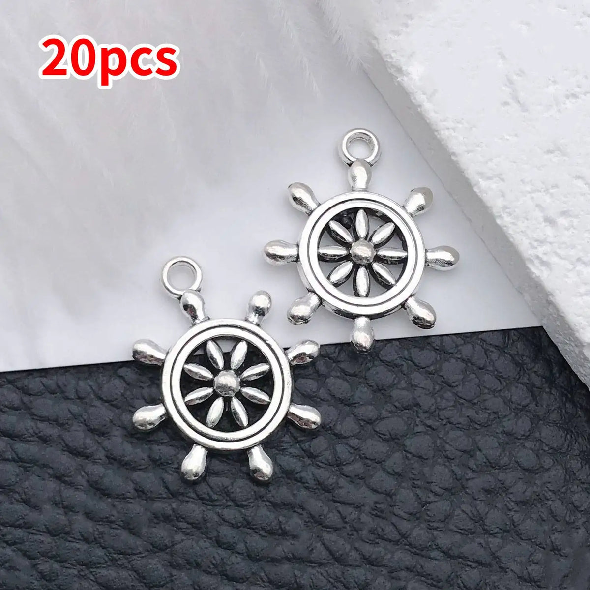 20 pieces of silver vintage ship anchor charms displayed on a black leather surface.