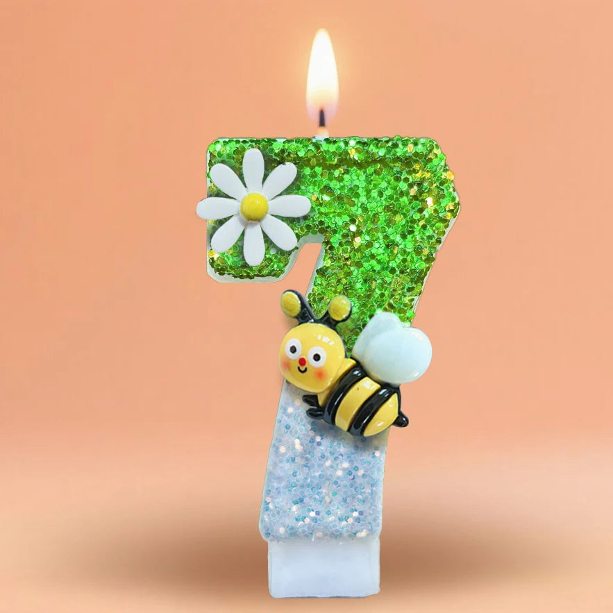 A birthday candle shaped like the number 7, decorated with green glitter and a bee figure.