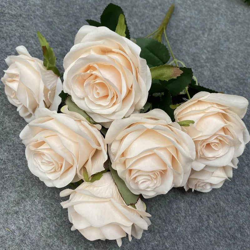 A bouquet of nine realistic pale pink silk roses arranged on a gray background.