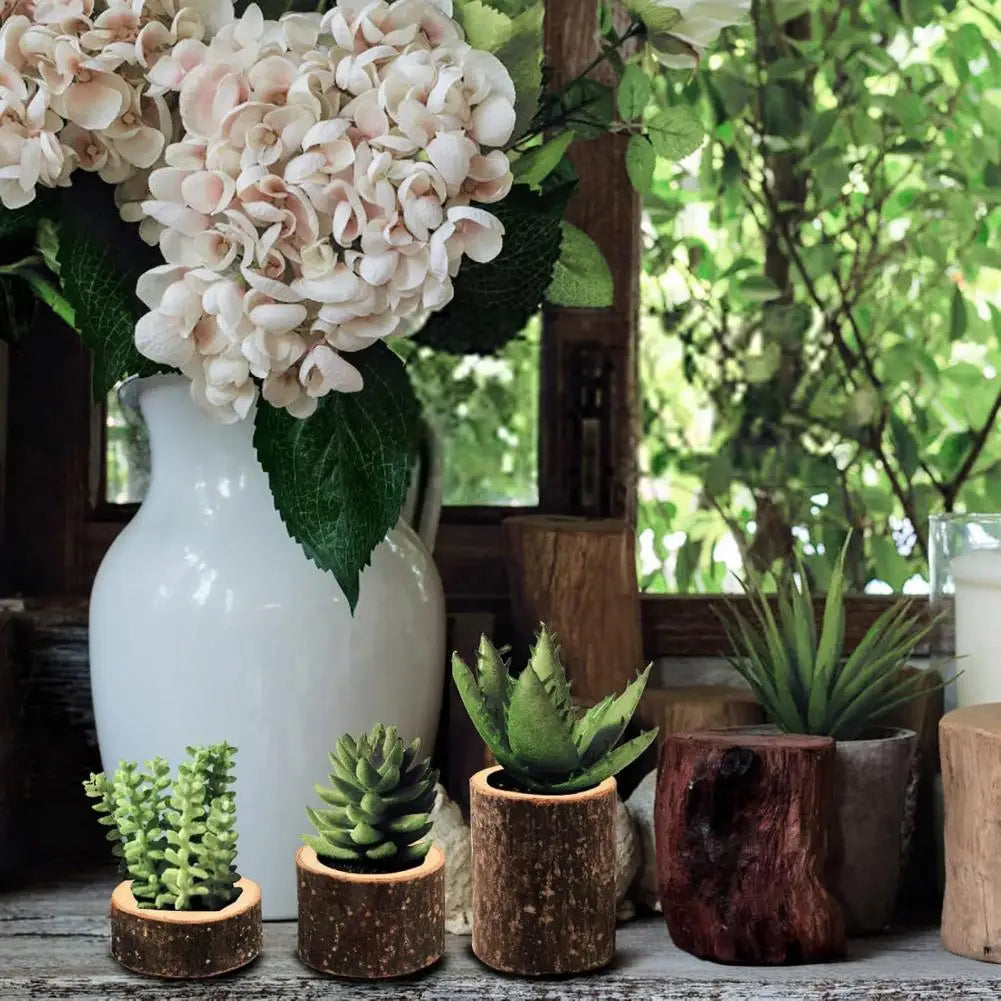 A set of rustic wooden stump candle holders displayed on a wooden surface with greenery and white flowers.