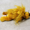 A fluffy yellow lion plush toy with long, flowing mane lying on a gray surface.
