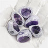 Several tumbled amethyst crystals are held in a gloved hand.