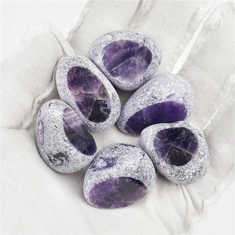 Several tumbled amethyst crystals are held in a gloved hand.