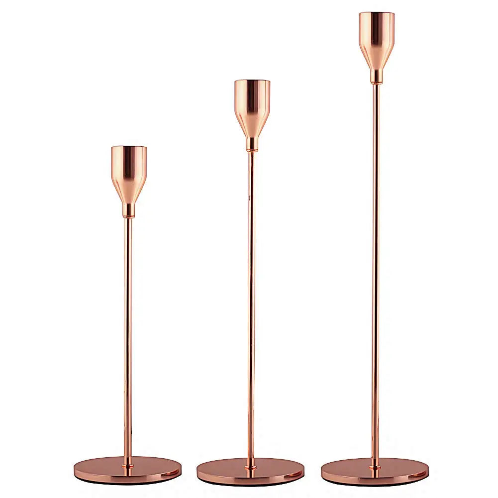 A set of three elegant rose gold metal candle holders with slender stems and round bases.