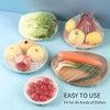 Reusable clear cling film used to wrap and store various fruits and vegetables like apples carrots and berries.